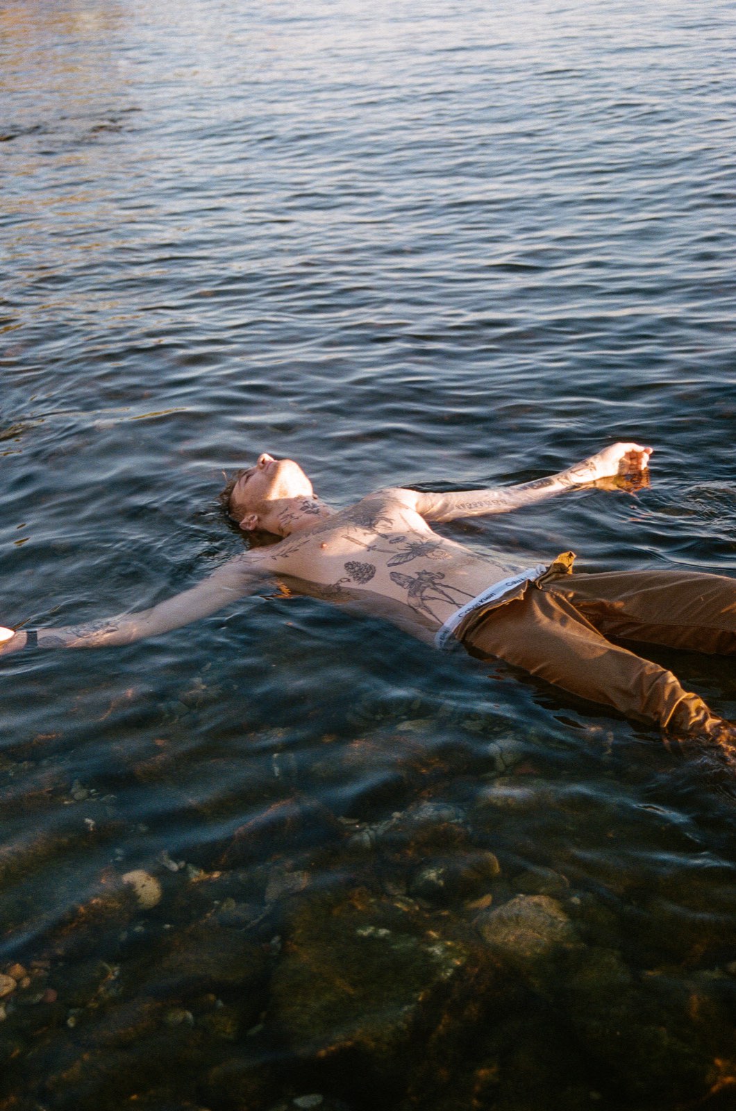 Martin floating on his back in a lake at golden hour, arms outstretched
