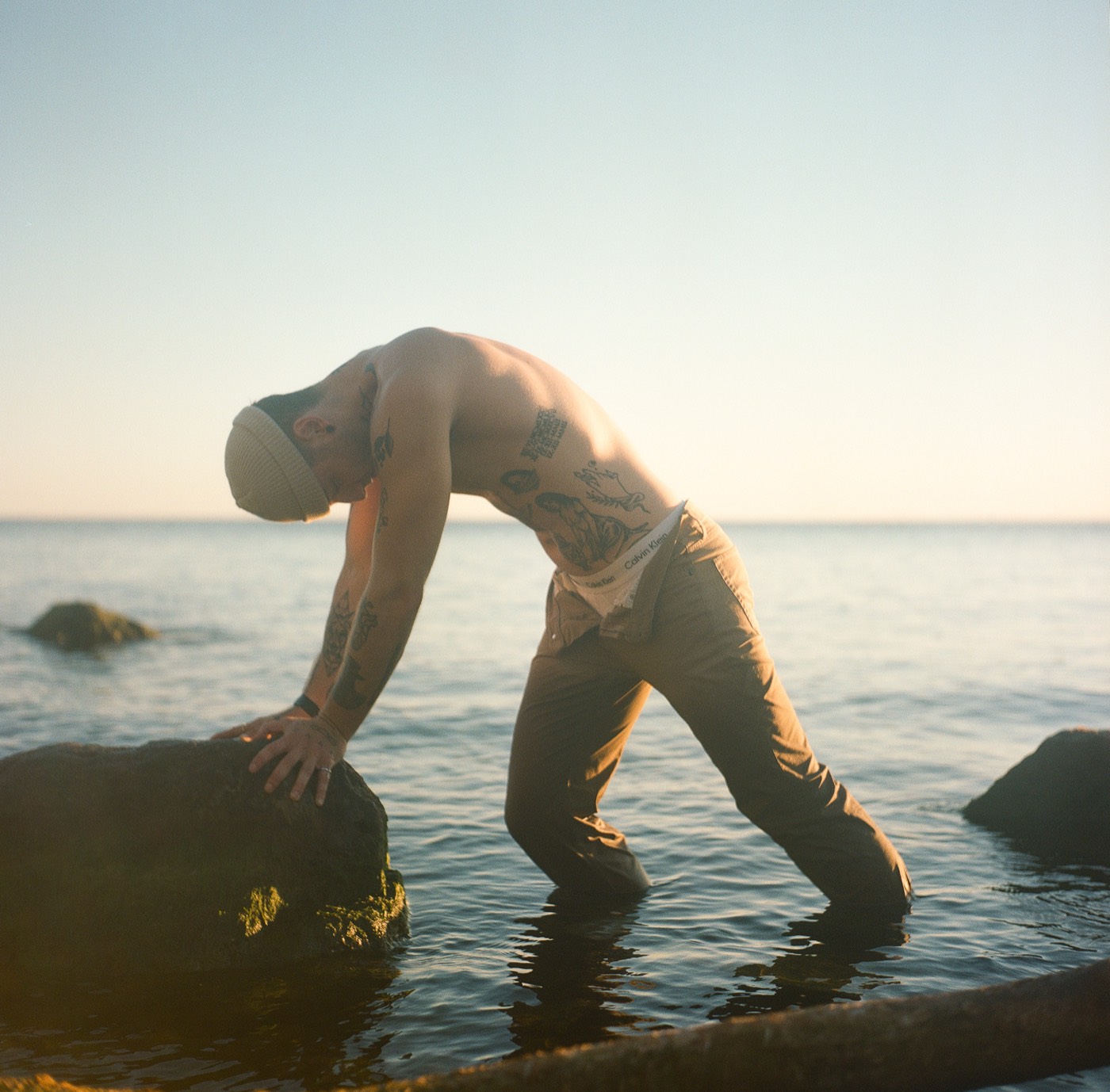 Martin stretching over a rock in the water